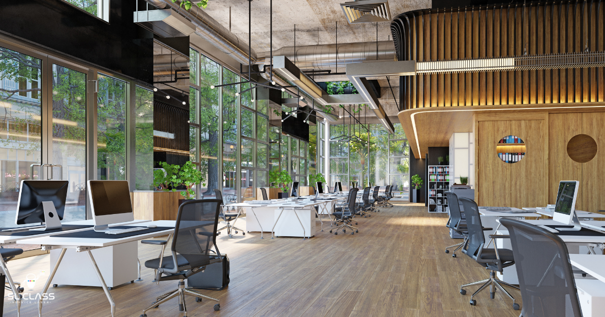 Open space moderne avec bureaux alignés, chaises ergonomiques et grandes baies vitrées laissant entrer la lumière naturelle.